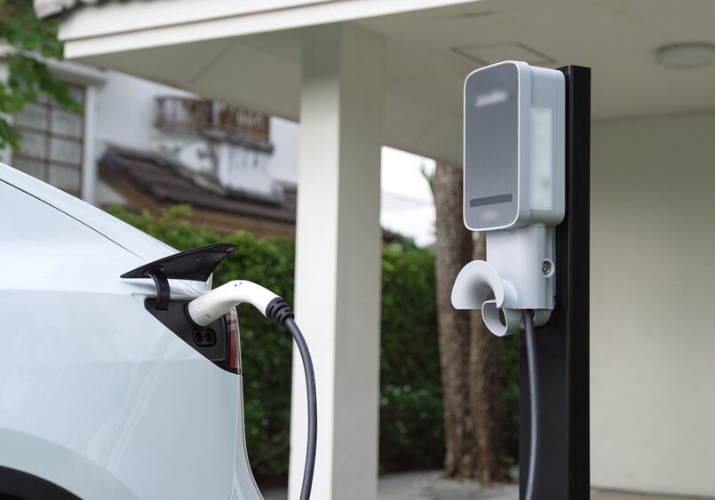 A professionally installed Level 2 electric vehicle charger connected to a car in a home garage, demonstrating safe residential electrical infrastructure.