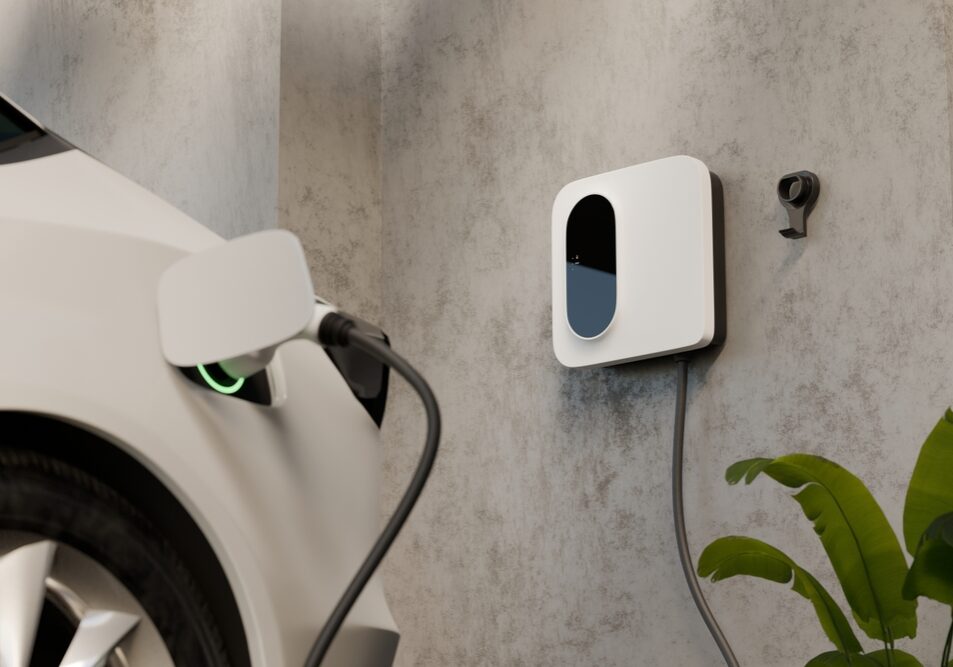 A newly installed Level 2 electric vehicle charging station mounted on a clean garage wall next to a parked car.